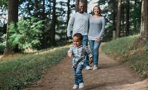 Image of two parents and a small child walking through the woods