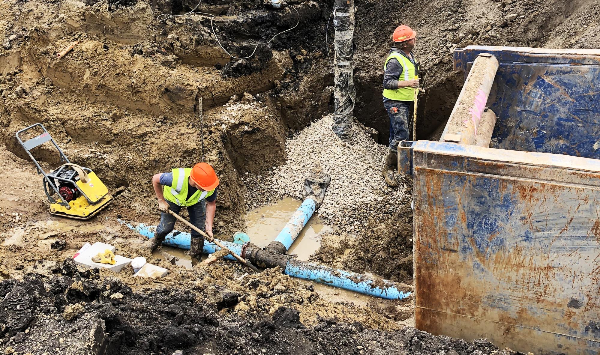 Image of two highway department workers digging out a brige abatement