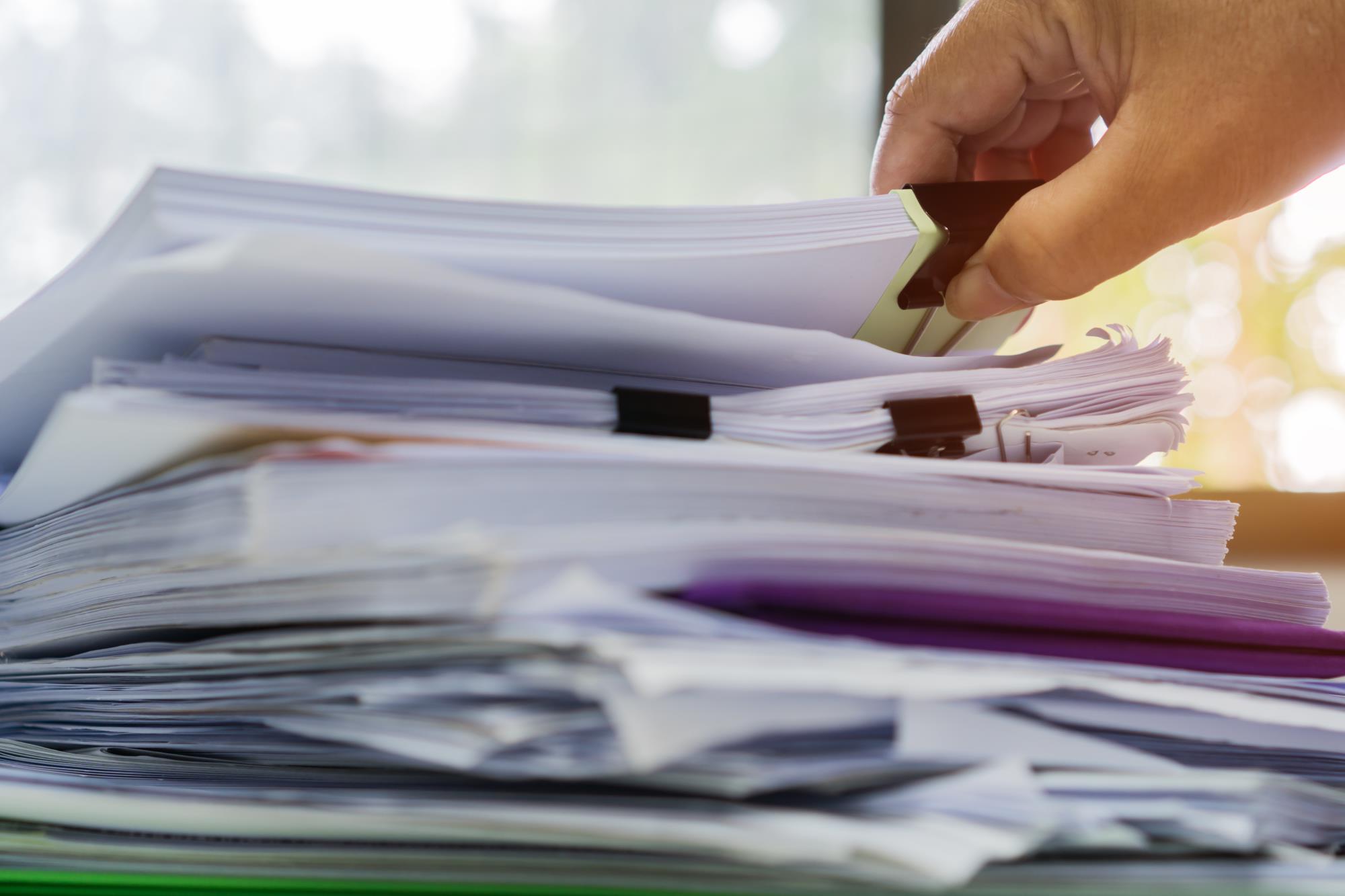 Image of person thumbing through a pile of documents